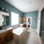 Spacious modern bathroom featuring a freestanding bathtub, wooden cabinets, and granite countertops.