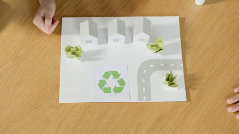 A paper model of a sustainable community featuring houses and recycling symbol, emphasizing eco-friendly living.