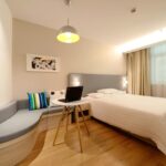 Modern hotel room featuring a bed, laptop, and stylish decor with ample lighting.