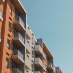 Contemporary apartment building with glass balconies under a clear blue sky.