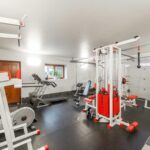 Modern interior design of new spacious fitness gym for home sport training and heavy weightlifting in garage of big house
